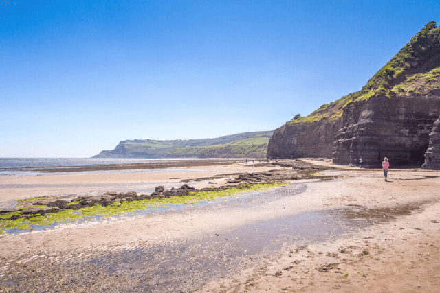 Woman walking along Robin Hood's Bay Beach