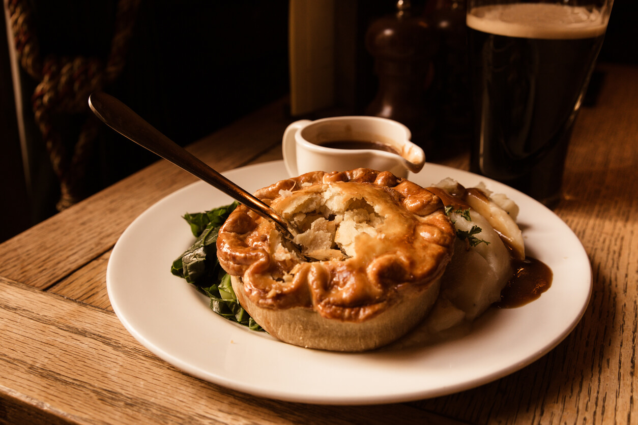 A meat pie and gravy in a traditional pub.