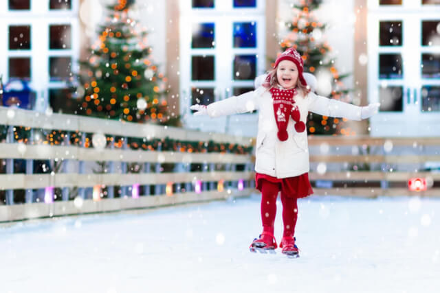 A young girl ice skating on an outdoor rink at Christmas 