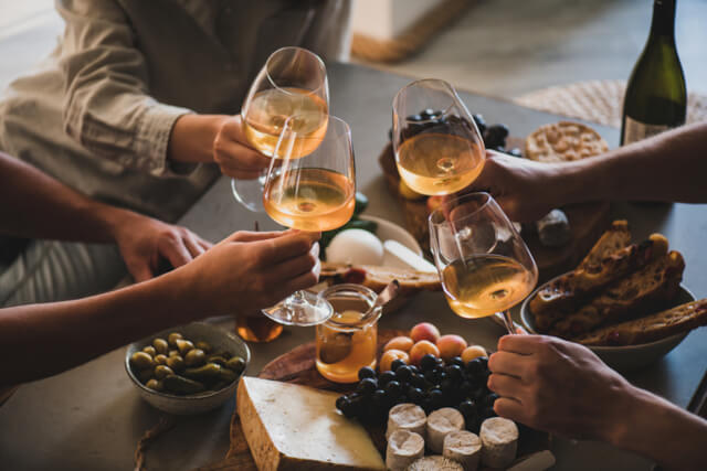 Friends toasting wine glasses over nibbles at a wine bar