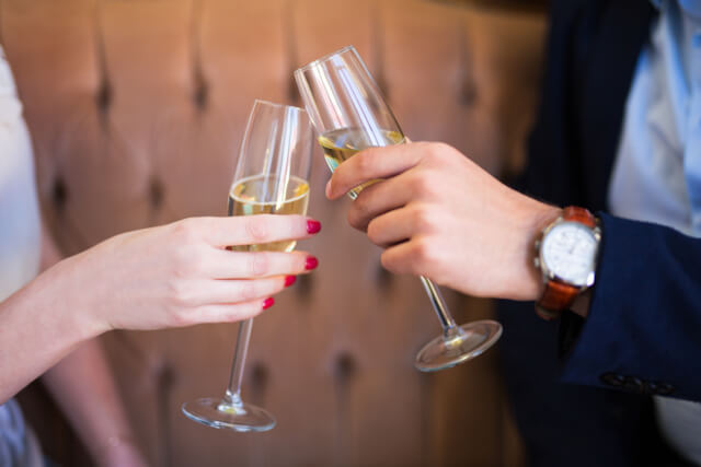 Two hands toasting a glass of prosecco