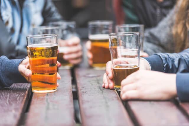 A group of friends gathered around a picnic table with half full pints of beer