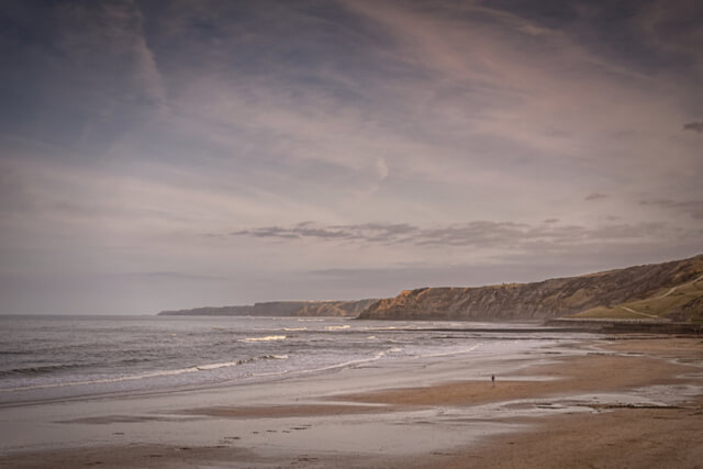 A view across an empty beach in Scarborough as the sun begins to set