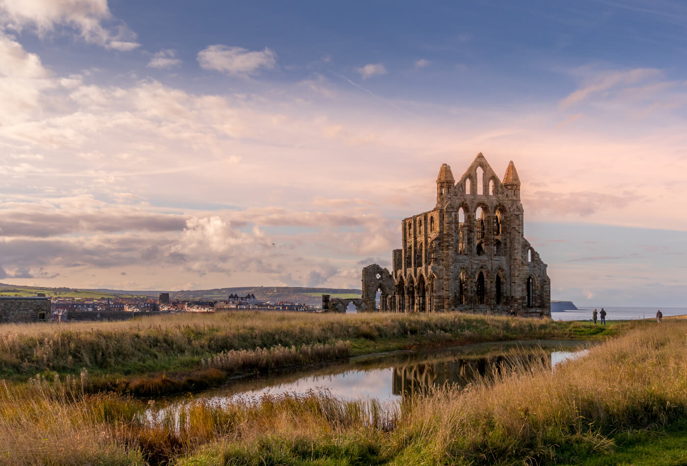 Whitby Abbey and the surrounding greenery as the sun is starting to set