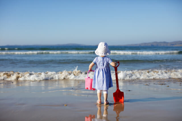 A little girl holding a bucket and spade on the beach