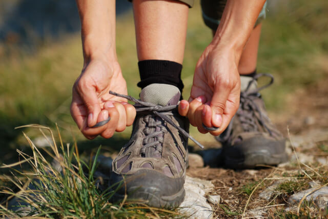 A person tying up the shoelaces of their walking boots