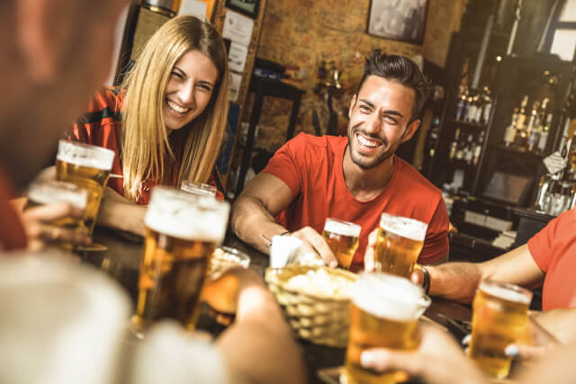 Adults sat around a table toasting pints of beer