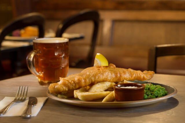 Fish and chips and a pint of beer on a table in a pub
