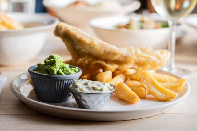 Fish and chips on a plate with mushy peas in a restaurant