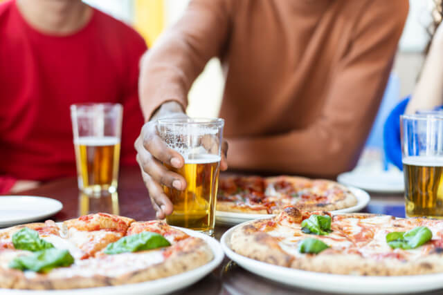 People sat around a table with pizza and beer