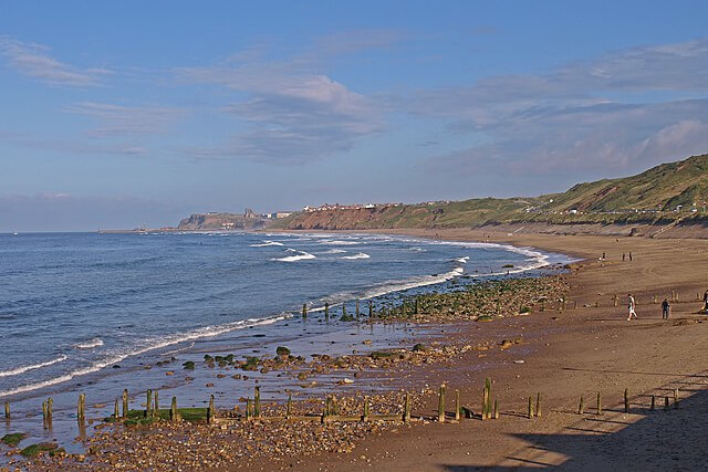 A view across the sand and shingle to the cliffs and sea beyond at Sandsend Beach