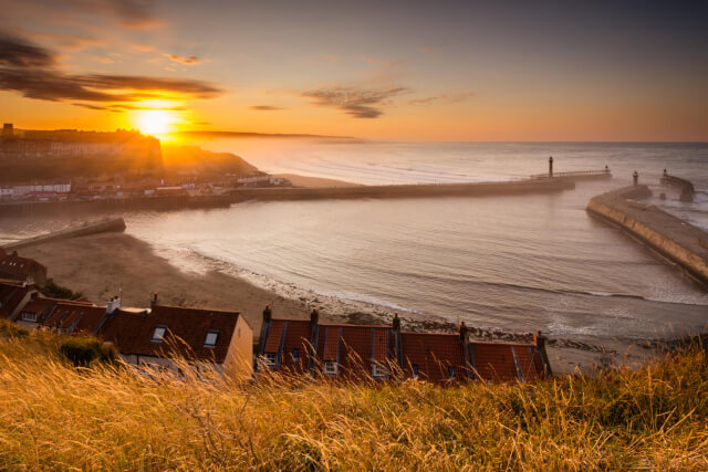 Looking down towards Whitby's harbour at sunset, with views across the North Sea